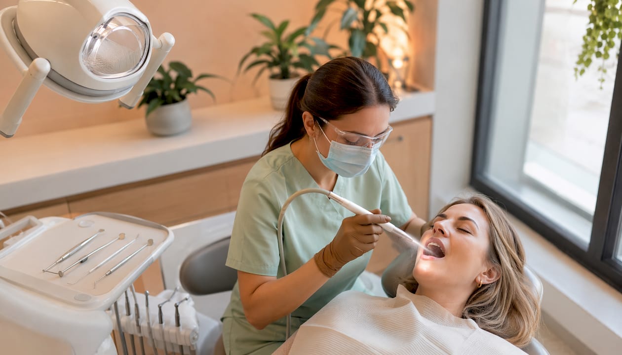 Igienista dentară efectuează o curățare profesională cu Air-Flow