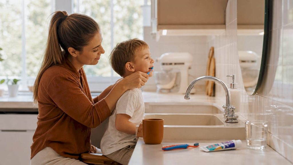 Mama îi curăță copilului dințișorii și gingiile, având grijă ca micuțul să aibă o igienă orală sănătoasă încă de la cele mai fragede vârste.
