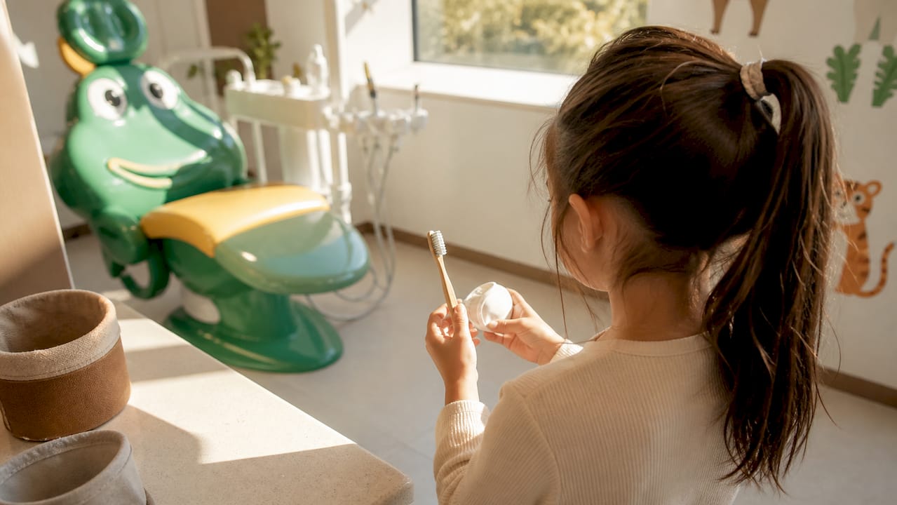 Copil care ține în mână un set de igienă dentară pentru cei mici