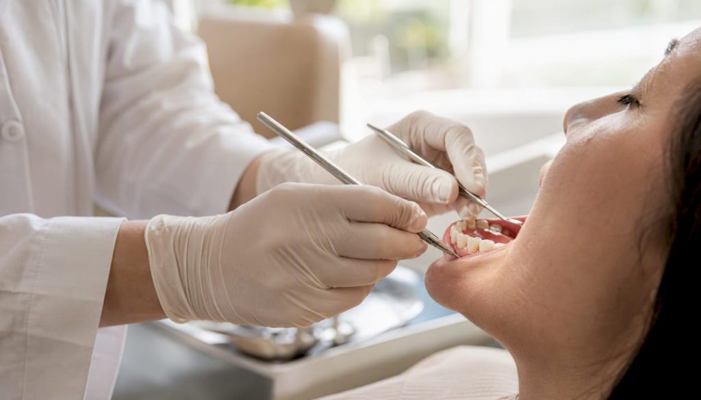 Medicul stomatolog efectuează detartrajul dinților în zona gingiilor care sângerează.
